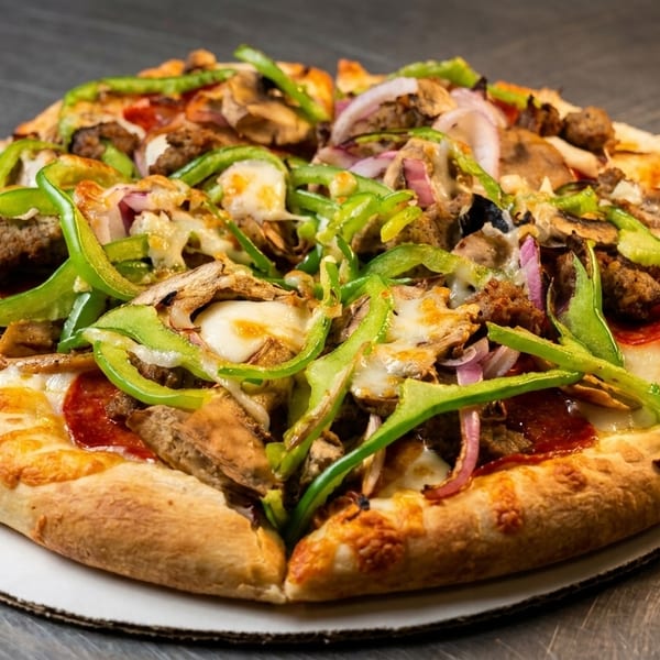 Whole pizza loaded with green peppers, red onions, mushrooms, sausage, and pepperoni.